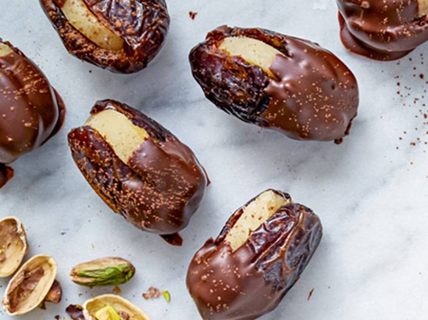 Chokladtäckta dadlar med marsipanfyllning och pistagenötter.
