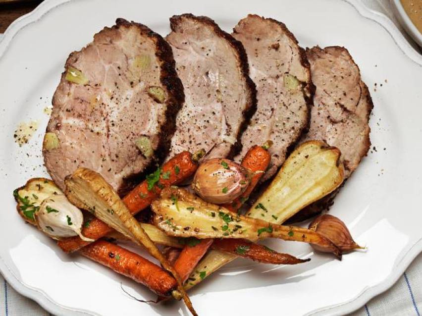 Rostad fläskkarré serveras med rostade morötter och palsternackor.