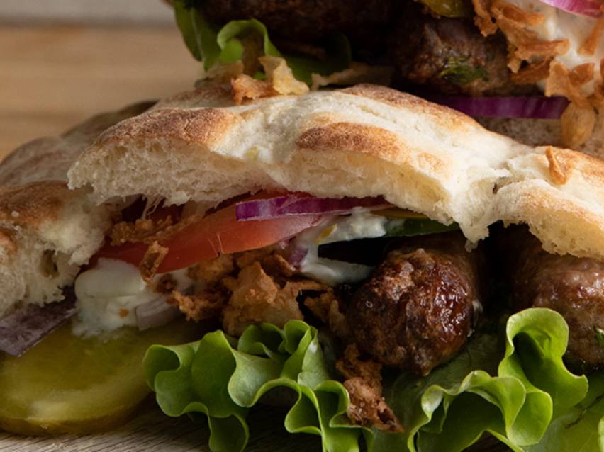 En läcker kebab i pita bröd med sallad, lök och sås.