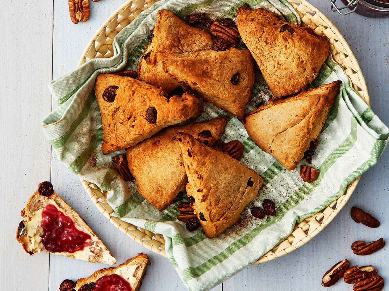En korg med trekantiga scones med russin och pekannötter, med två smörade scones med sylt.