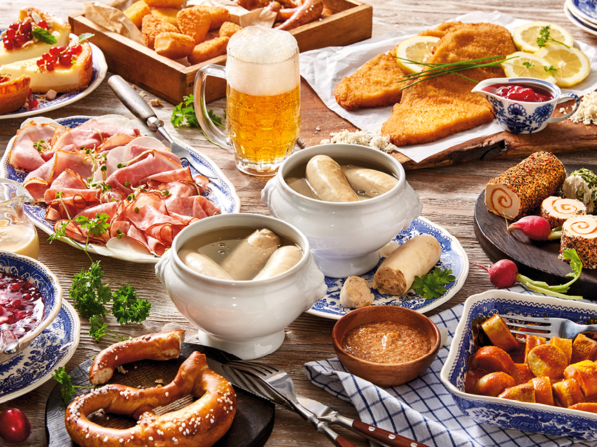 En festlig spridning av tysk mat, inklusive schnitzel, korv, kringlor och ostkaka.