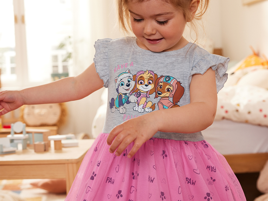 En liten flicka bär en söt klänning med Paw Patrol-motiv.