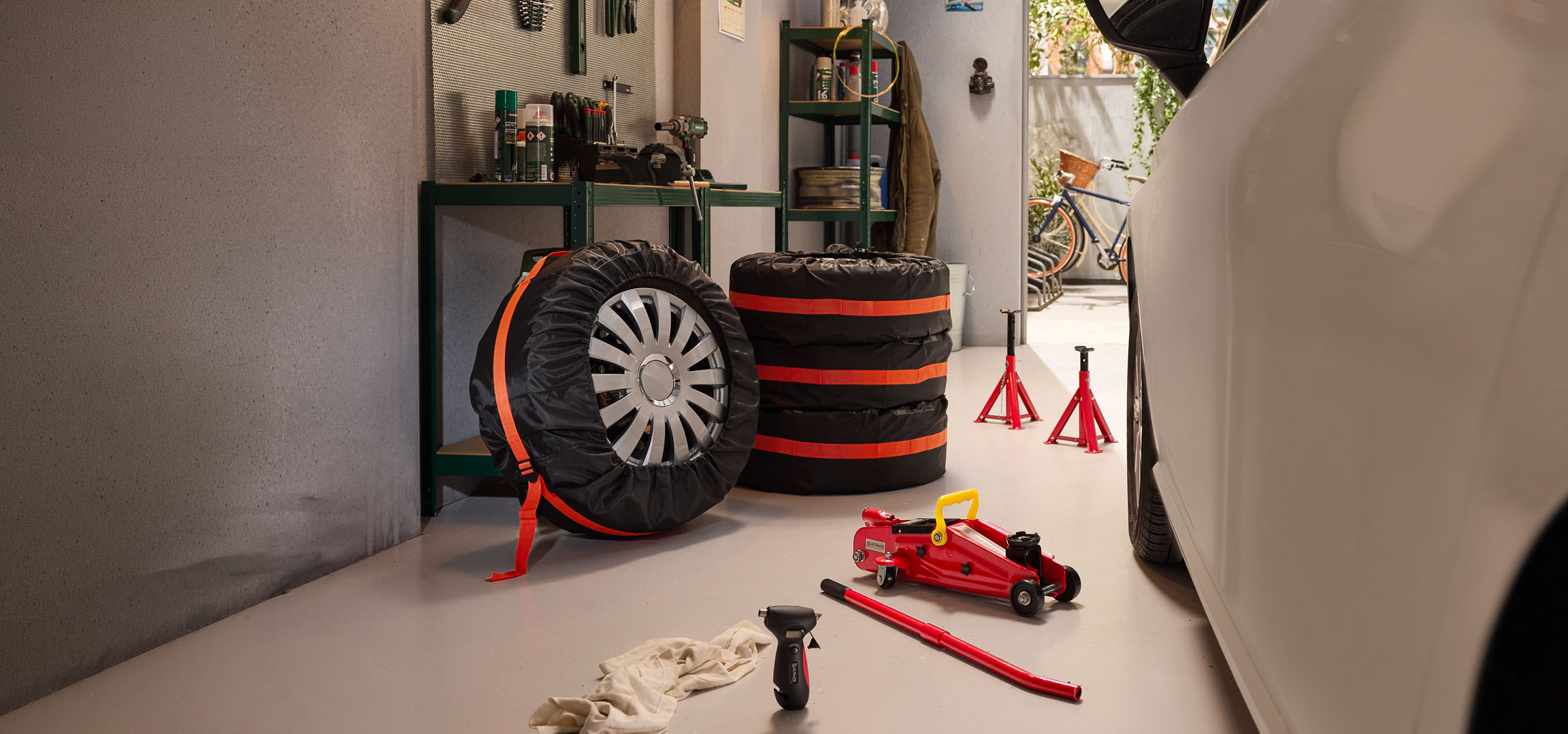 Vinterdäck förvarade i ett garage med en domkraft och pallbockar.