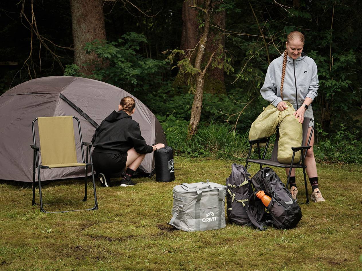 Två personer packar upp campingutrustning, inklusive Crivit kylväska och tält.