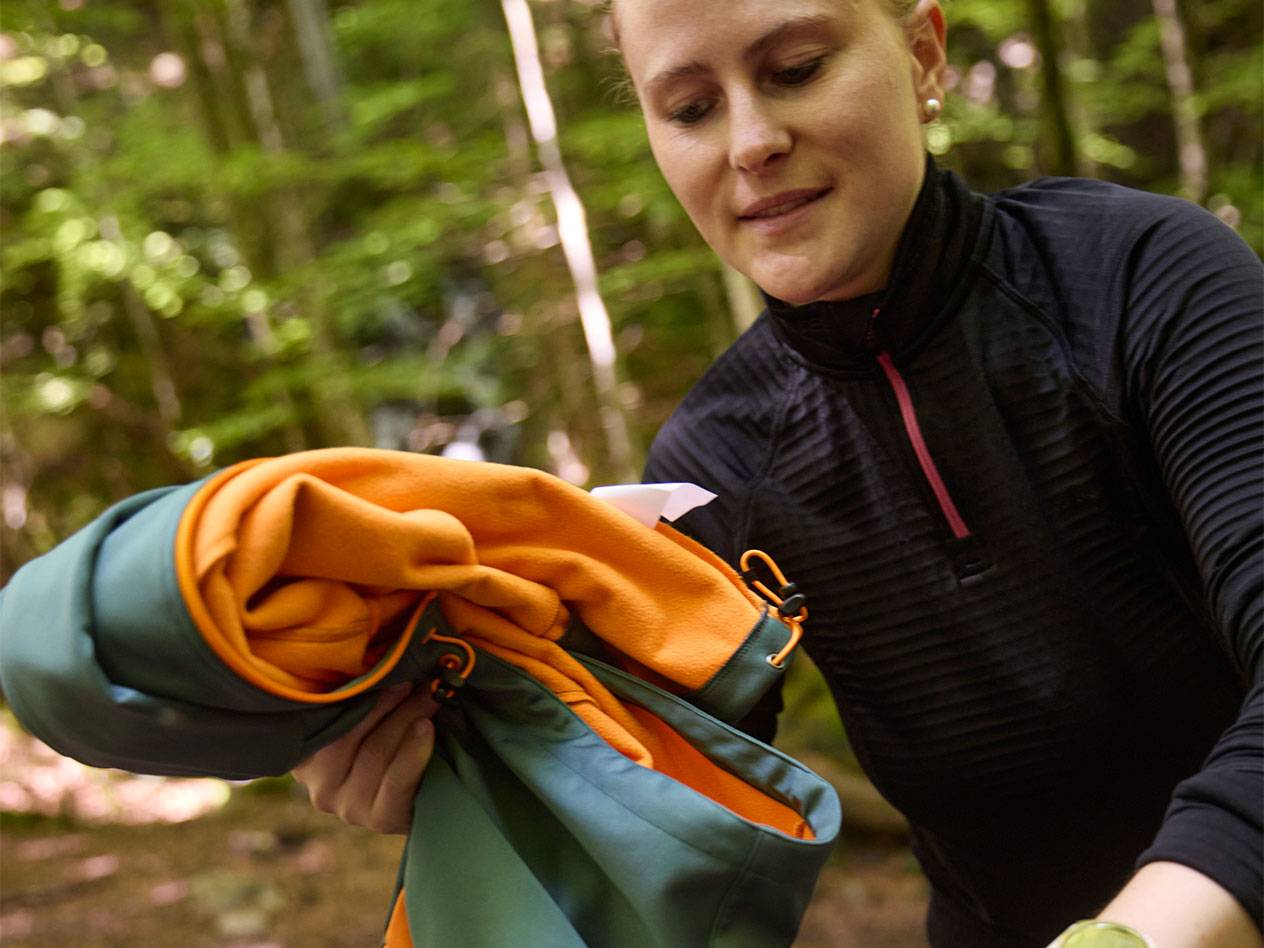 Kvinna i en skog viker en sportjacka.