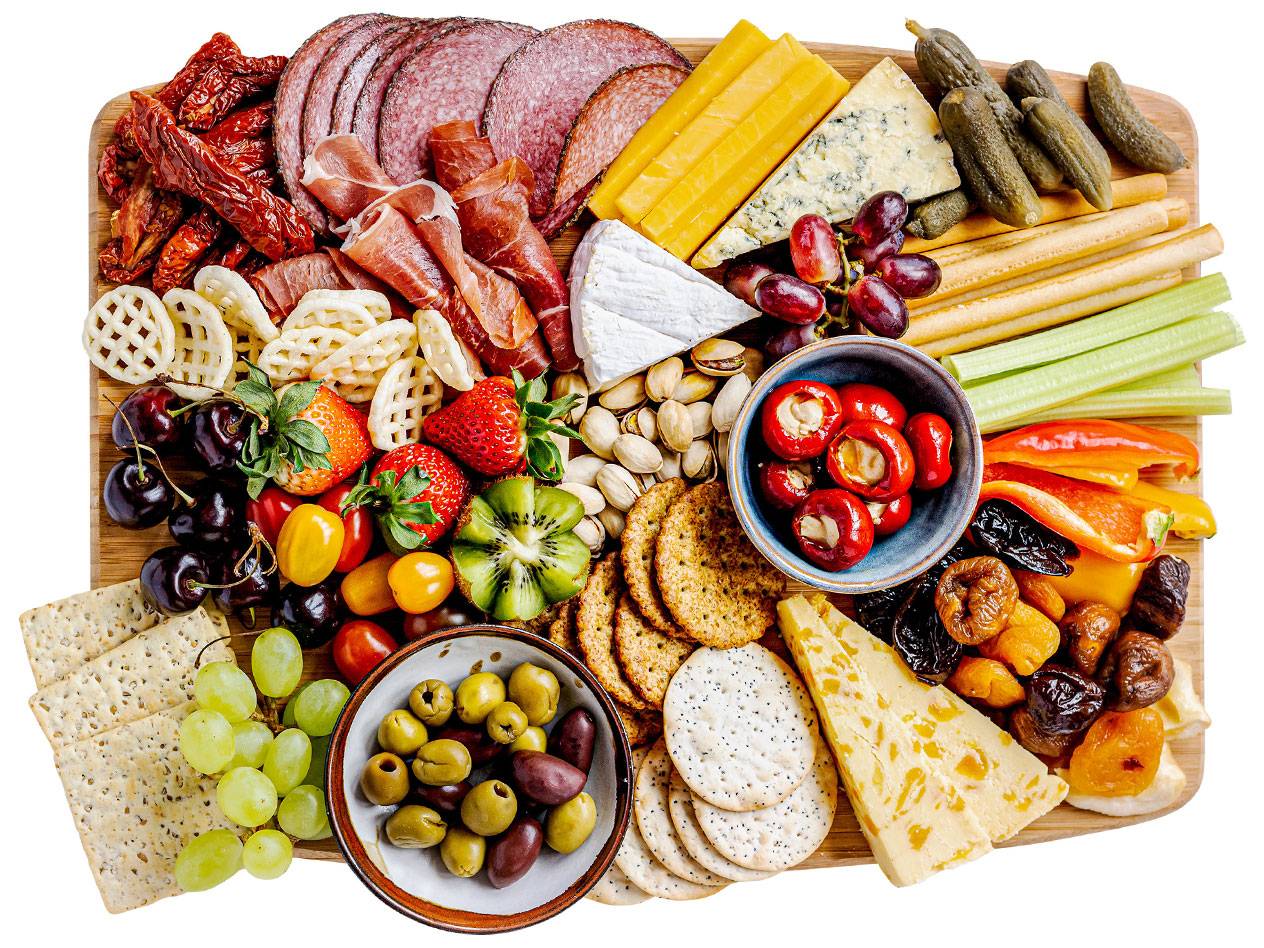 En charkbricka med ost, charkuterier, frukt, grönsaker, kex och nötter.