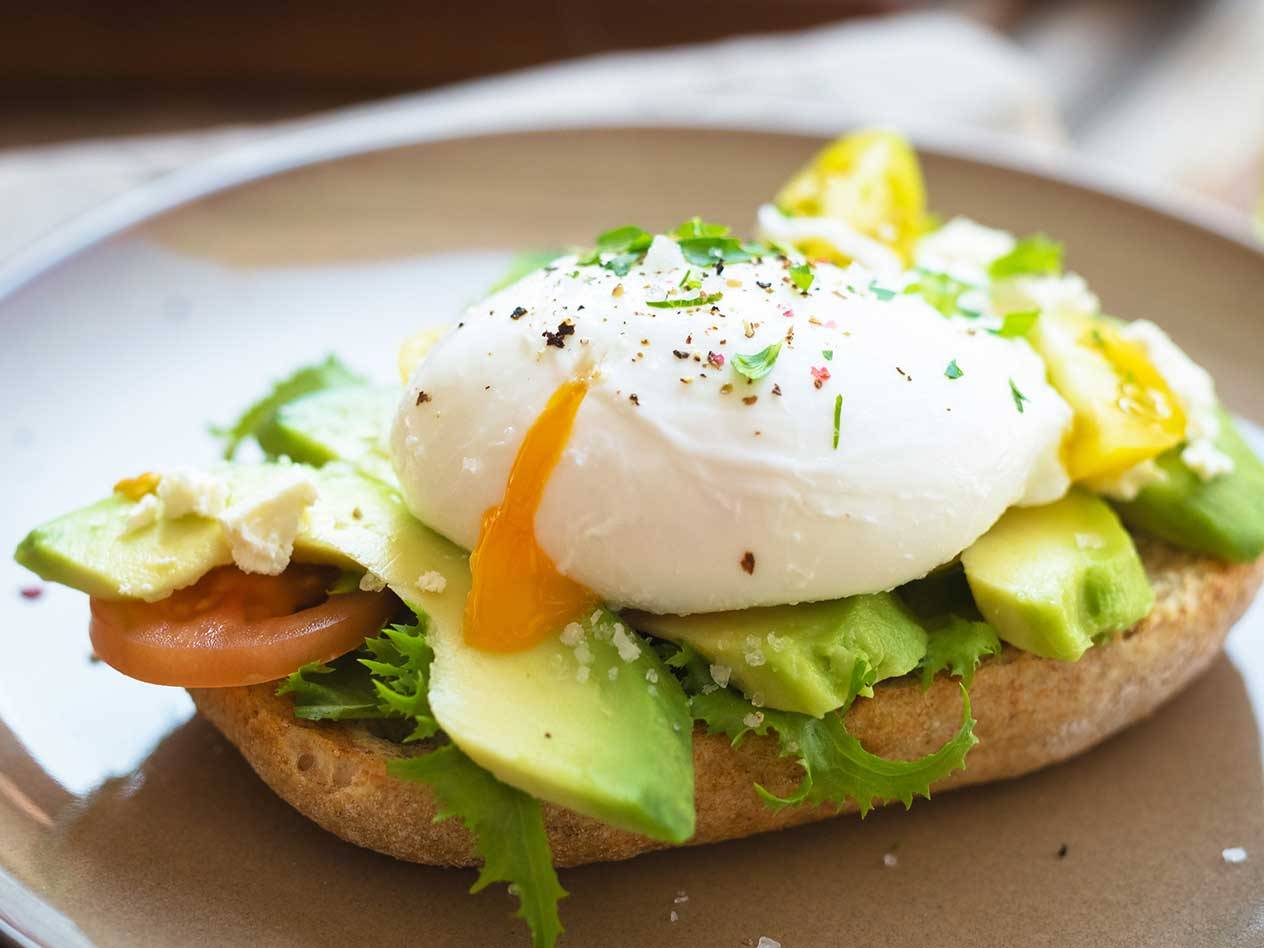 Avokadotoast med pocherat ägg, sallad, tomat och fetaost.