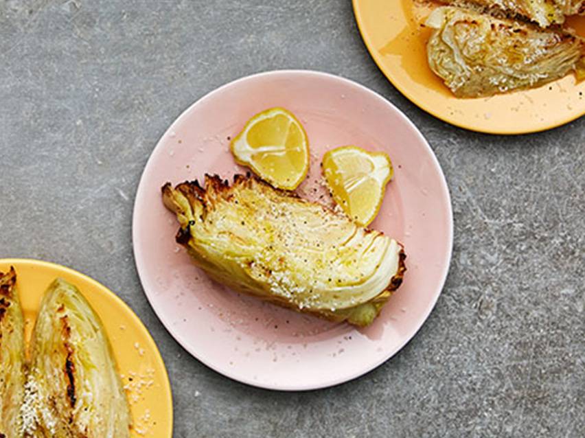 Rostad vitkål och citron på rosa och gula tallrikar.