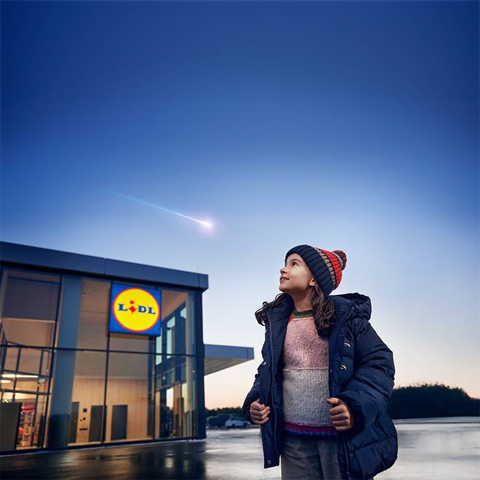 En flicka tittar på ett stjärnfall över en Lidl-butik.